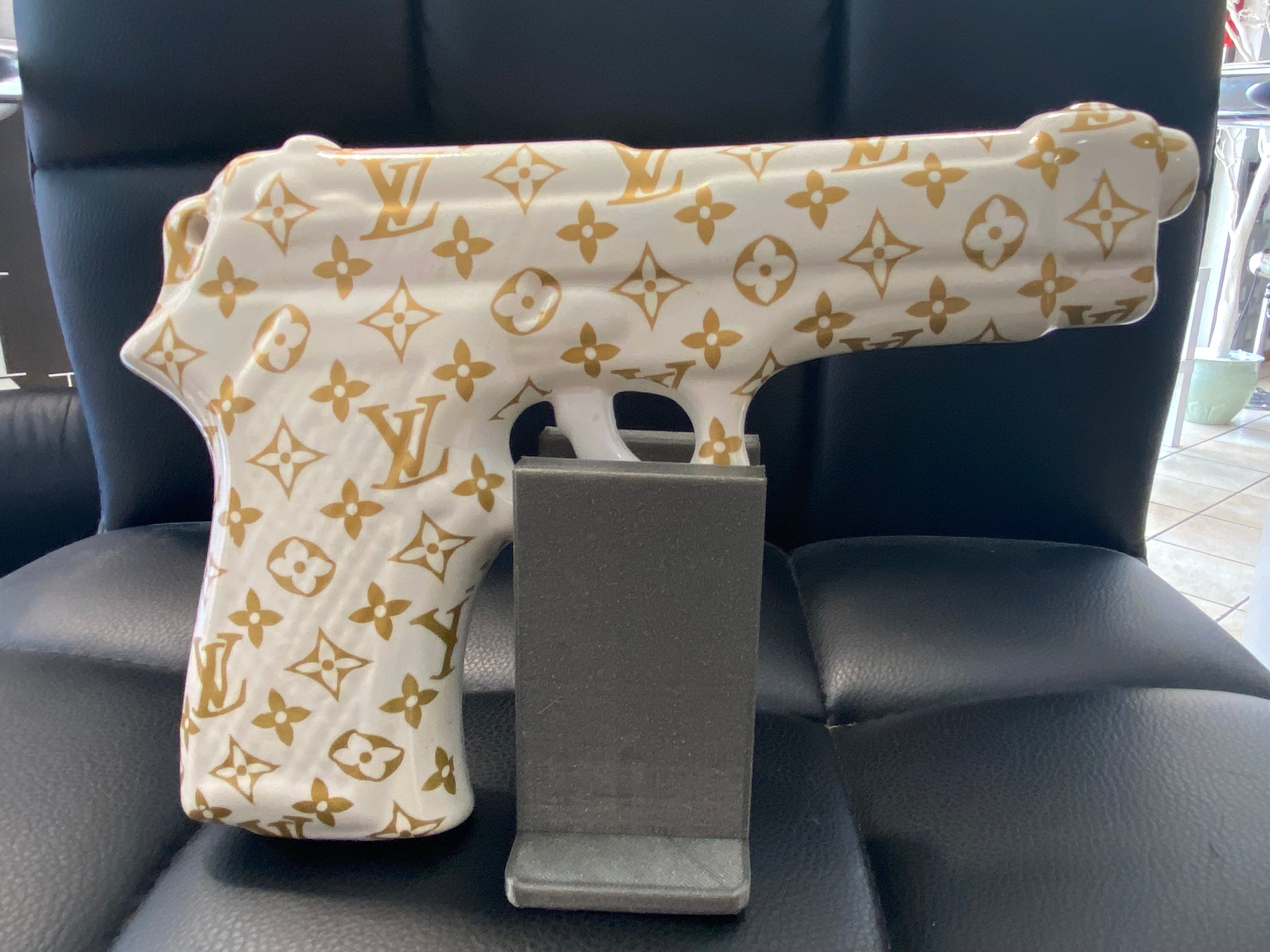 Opera pop art MY GUN n.1 in porcellana con motivi oro su fondo bianco, vista dall’alto.