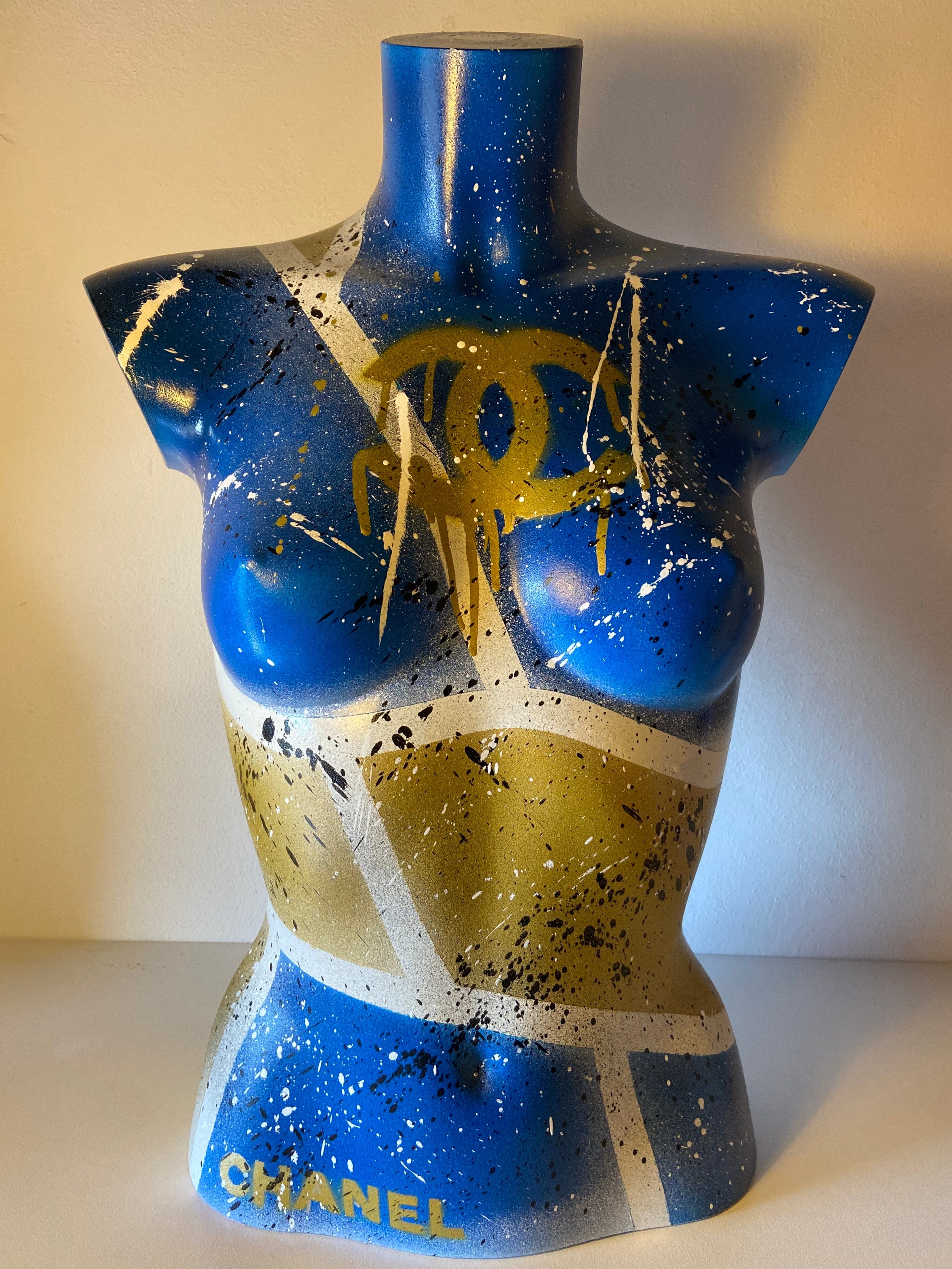 Dettaglio superiore della scultura Lady Chanel, torso femminile blu e oro con dripping artistico.